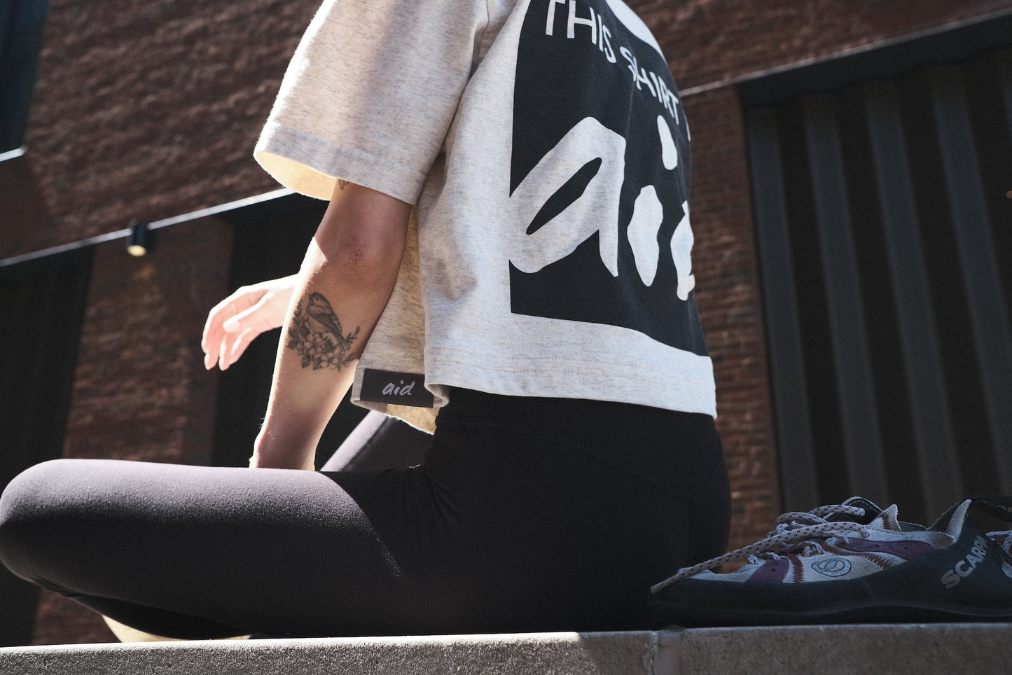 Woman sitting, wearing the Crop Top by Aid Climbing Company