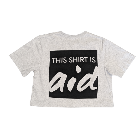 Cream t-shirt with black square and white text, says This Shirt is Aid